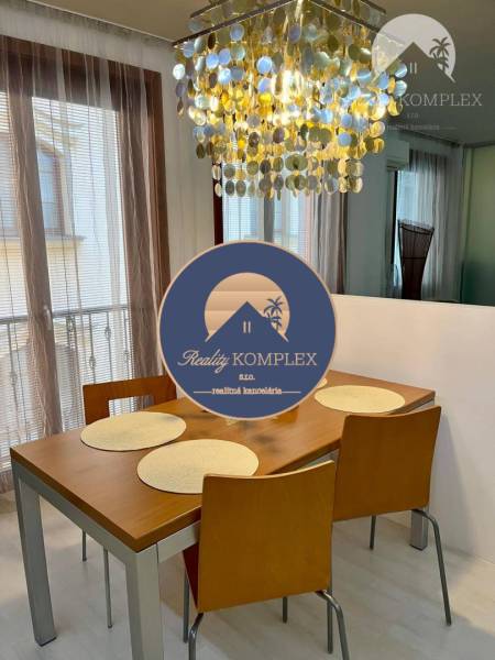 Vám EXKLUZÍVNE ponúka NA PRENÁJOM moderný 2 iz - Jedálenský stôl so stoličkami pod výrazným lustrom v 2-izbovom byte.