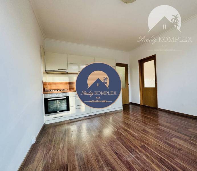 Vám ponúka 1 izbový byt vo VYHĽADÁVANEJ lokali - Interiér 1-izbového bytu s kuchyňou a podlahou s dreveným dekorom.