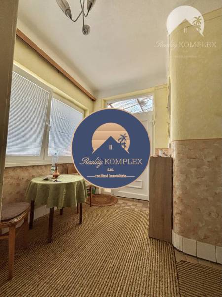 Vám ponúka na predaj 4 izbový rodinný dom  s r - Interiér rodinného domu s kobercovou podlahou, stolom a stoličkou.