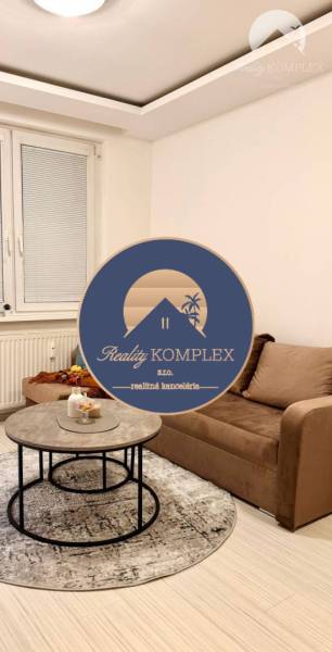 Vám ponúka garsonku vo VYHĽADÁVANEJ lokalite m - Svetlá izba Rekreačného apartmánu s pohovkou, oknom a stolíkom na podlahe s dreveným dekorom.