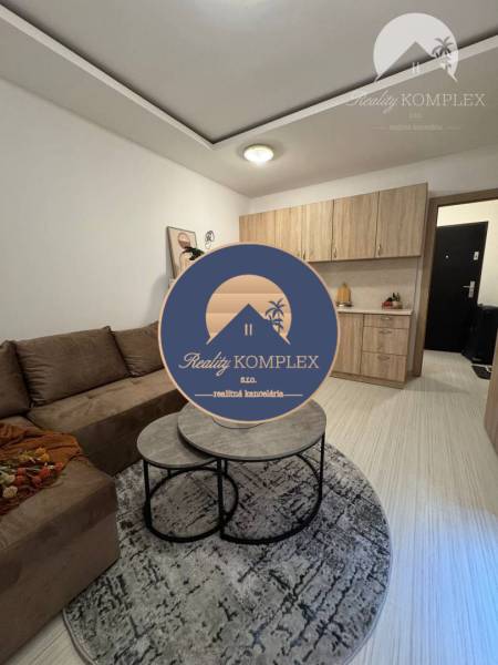 Vám ponúka garsonku vo VYHĽADÁVANEJ lokalite m - Obývací priestor s podlahou s dreveným dekorom v Rekreačnom apartmáne, útulná pohovka a konferenčný stolík.