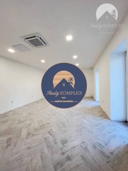 Vám ponúka  na predaj budovu na BÝVANIE aj PODN - Priestranná izba s dlažbou, biele steny, zasadená v útulnej budove.