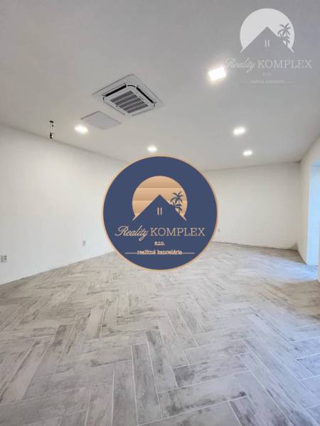 Vám ponúka  na predaj budovu na BÝVANIE aj PODN - Prázdna miestnosť, biele steny, šikmá podlaha, osvetlená, klimatizácia, interiér budovy.