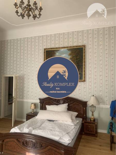 Vám ponúka do PRENÁJMU čarovný, úplne zrekonštr - Spálňa v rodinnom dome s posteľou, lustrom a jemnou tapetou, podlaha s dreveným dekorom.