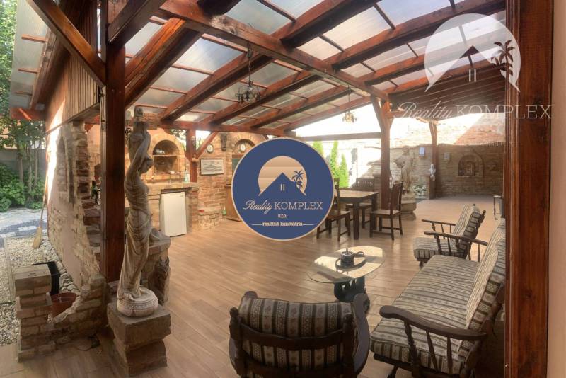 Vám ponúka do PRENÁJMU čarovný, úplne zrekonštr - Krytá terasa v rodinnom dome s tehlovou stenou, drevenými trámami a podlahou s dreveným dekorom.