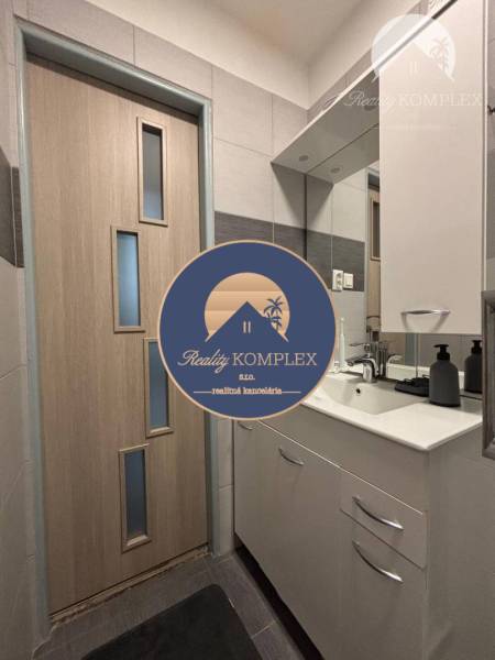 Vám ponúka exkluzívne na predaj moderný, komple - Kúpeľňa v 1-izbovom byte s umývadlom, zrkadlom a drevenými dverami.
