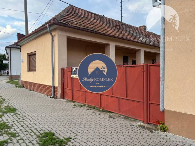 Reality KOMPLEX Vám ponúka EXKLUZÍVNE na predaj rodinný dom, ktorý sa  - Rodinný dom vo Veľkom Mederi s červenou bránou a tehlovým základom.