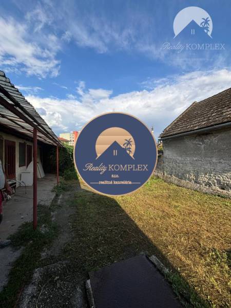 Reality KOMPLEX Vám ponúka EXKLUZÍVNE na predaj rodinný dom, ktorý sa  - Dvor rodinného domu vo Veľkom Mederi s viditeľnými strechami dvoch budov.