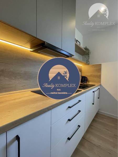 Vám ponúka na Prenájom 2-izbový byt s loggiou  - Kuchyňa v 2-izbovom byte s podlahou s dreveným dekorom a zabudovanými skrinkami.