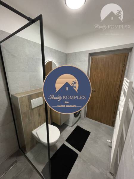 Vám ponúka na Prenájom 2-izbový byt s loggiou  - Kúpeľňa v 2-izbovom byte s toaletou, práčkou a sprchovacím kútom s jednoduchým dizajnom.