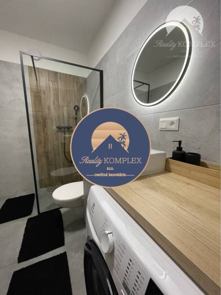 Vám ponúka na Prenájom 2-izbový byt s loggiou  - Kúpeľňa v 2-izbovom byte s práčkou, sprchovým kútom a podlahou s dreveným dekorom.