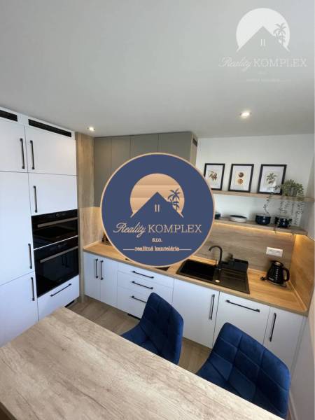 Vám ponúka na Prenájom 2-izbový byt s loggiou  - Kuchyňa v 2-izbovom byte s dreveným dekorom na pracovnej doske a podlahe.