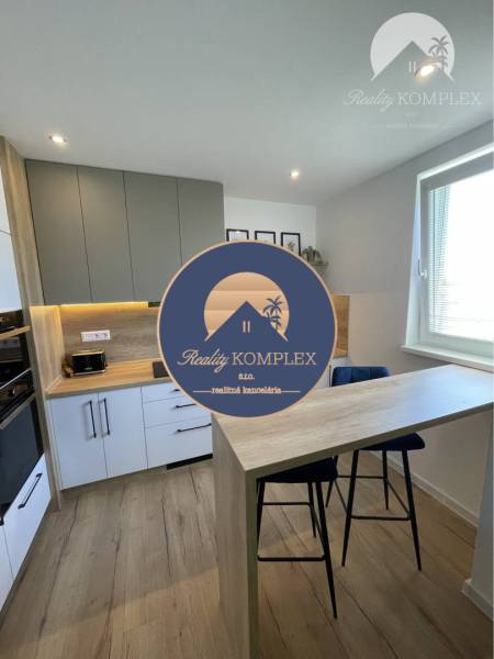 Vám ponúka na Prenájom 2-izbový byt s loggiou  - Kuchyňa v 2-izbovom byte s podlahou s dreveným dekorom a minimalistickým nábytkom.