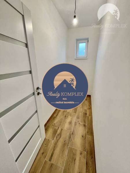 Vám ponúka modernú 4-izbovú novostavbu v Dunajs - Úzka chodba s bielymi stenami v rodinnom dome, podlaha s dreveným dekorom.