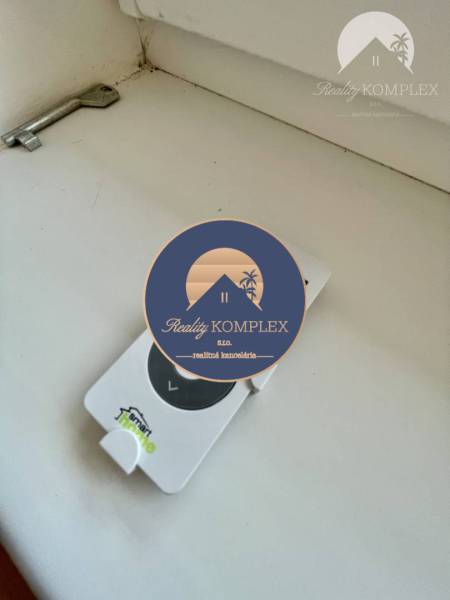 Vám ponúka modernú 4-izbovú novostavbu v Dunajs - Kľúč a ovládač ležia na bielom povrchu v Rodinnom dome.