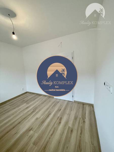 Vám ponúka modernú 4-izbovú novostavbu v Dunajs - Prázdna miestnosť s podlahou s dreveným dekorom v rodinnom dome s bielymi stenami.