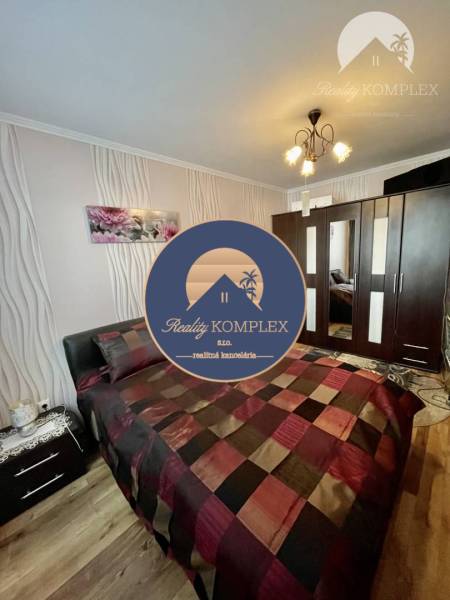 Vám ponúka 3-izbový byt s loggiou po kompletnej - Spálňa v 3-izbovom byte s elegantným nábytkom a podlahou s dreveným dekorom.