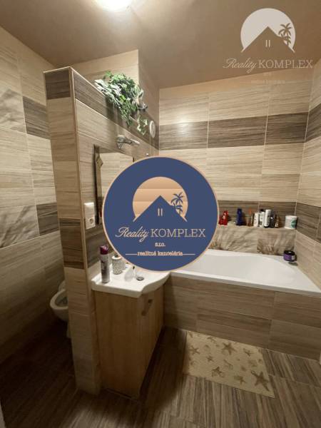 Vám ponúka 3-izbový byt s loggiou po kompletnej - Kúpeľňa s vaňou a podlahou s dreveným dekorom v 3-izbovom byte.