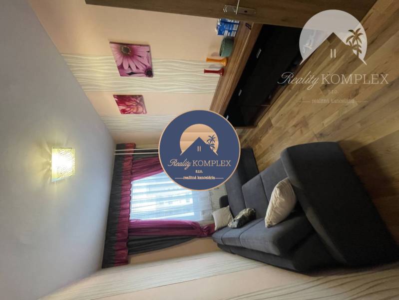 Vám ponúka 3-izbový byt s loggiou po kompletnej - Obývacia izba s podlahou s dreveným dekorom, pohovkou a dekoratívnymi obrazmi v 3-izbovom byte.