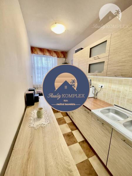 Vám ponúka 3-izbový byt s loggiou po kompletnej - Kuchyňa v 3-izbovom byte s podlahou s dreveným dekorom a šachovnicovým vzorom.