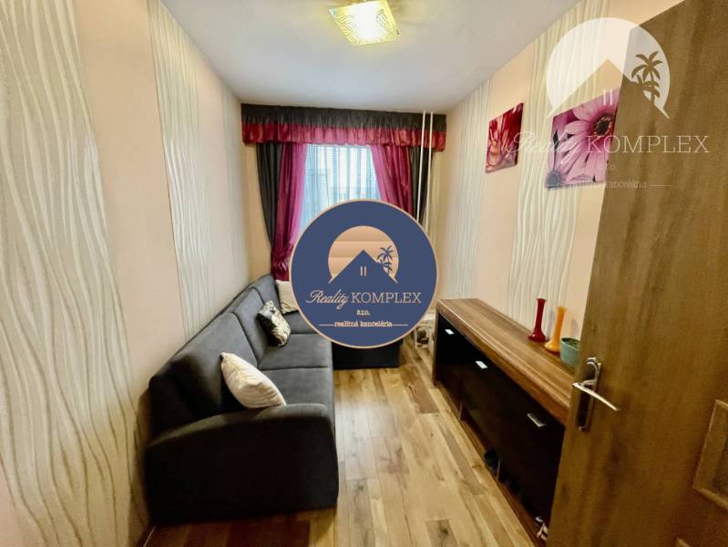 Vám ponúka 3-izbový byt s loggiou po kompletnej - Obývací priestor v 3-izbovom byte s podlahou s dreveným dekorom a elegantným osvetlením.