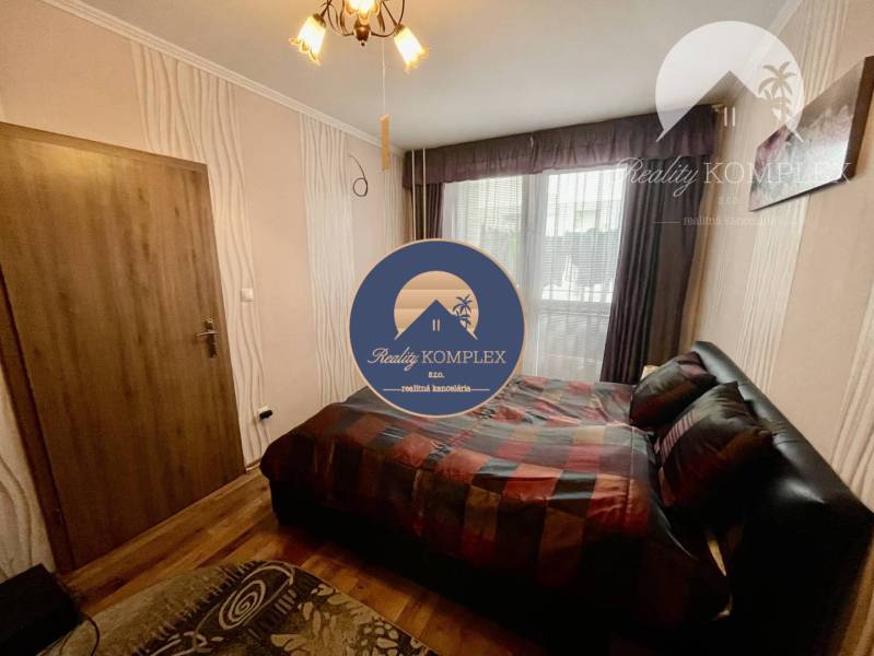 Vám ponúka 3-izbový byt s loggiou po kompletnej - Spálňa v 3-izbovom byte s podlahou s dreveným dekorom, veľké okno, posteľ.