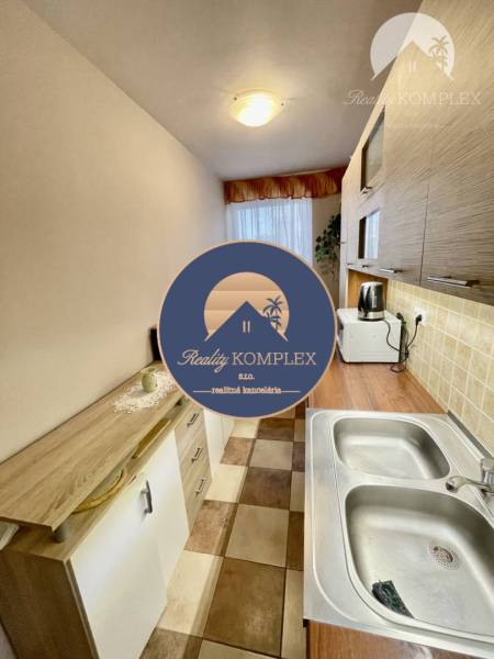 Vám ponúka 3-izbový byt s loggiou po kompletnej - Kuchyňa v 3-izbovom byte s dlažbou a dreveným dekorom na skrinkách.