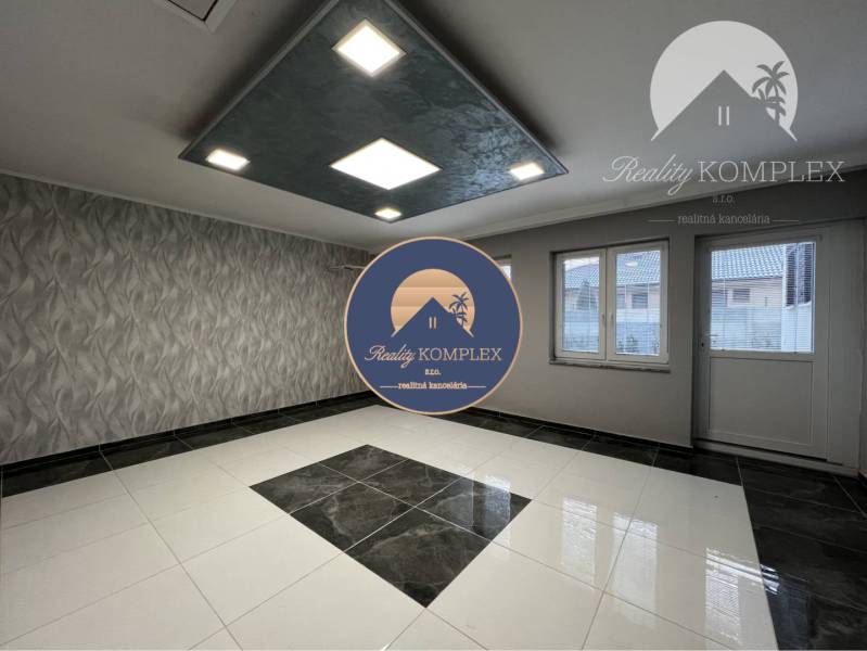 Vám ponúka na PREDAJ kompletne zrekonštruovaný  - Miestnosť v rodinnom dome s dlažbou, vzorovanou tapetou a zníženým stropom so svietidlami.