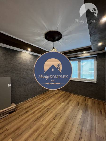 Vám ponúka na PREDAJ kompletne zrekonštruovaný  - Miestnosť rodinného domu s tmavou stenou, podlahou s dreveným dekorom a zaujímavým stropom.