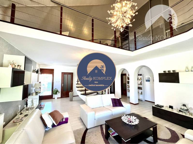 Ponúka na PREDAJ zrekonštruovaný 5 izbový podpi - Luxusná obývacia izba v rodinnom dome s dekoráciami a schodiskom na poschodie.