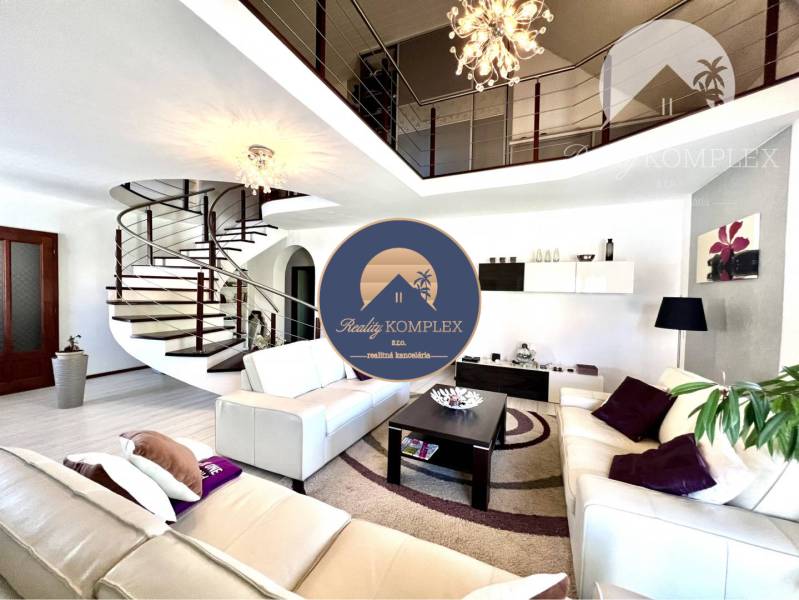 Ponúka na PREDAJ zrekonštruovaný 5 izbový podpi - Obývacia izba v rodinnom dome so špirálovitým schodiskom a elegantným osvetlením.