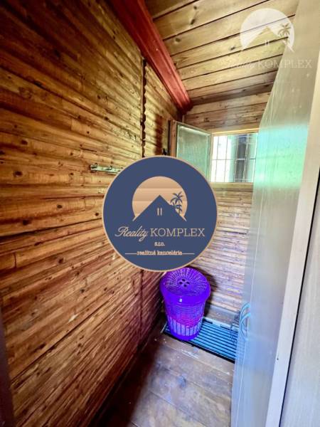 Ponúka na PREDAJ viničný domček s priestranným  - Chata s drevenými stenami a fialovým košom na prádlo.