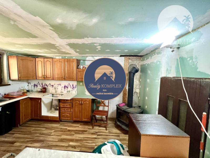 Ponúka na PREDAJ viničný domček s priestranným  - Kuchyňa v Chate s dreveným nábytkom, sporákom a laminátovou podlahou.