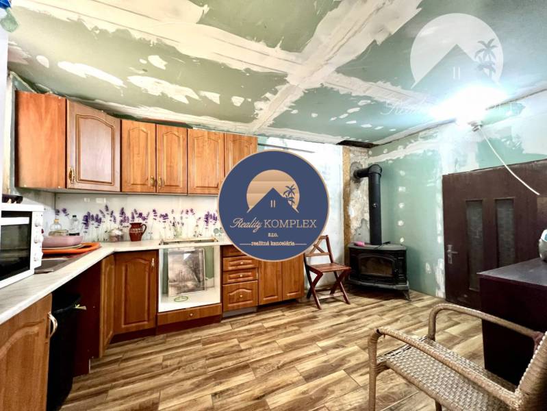 Ponúka na PREDAJ viničný domček s priestranným  - Kuchyňa v chate s drevenými skrinkami, sporákom a dlažbou.