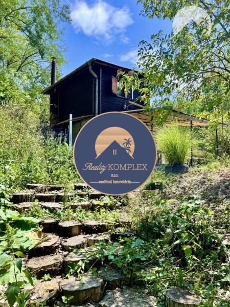 Ponúka na PREDAJ viničný domček s priestranným  - Chata v Kameníne so schodmi z dreva, obklopená zeleňou a stromami.