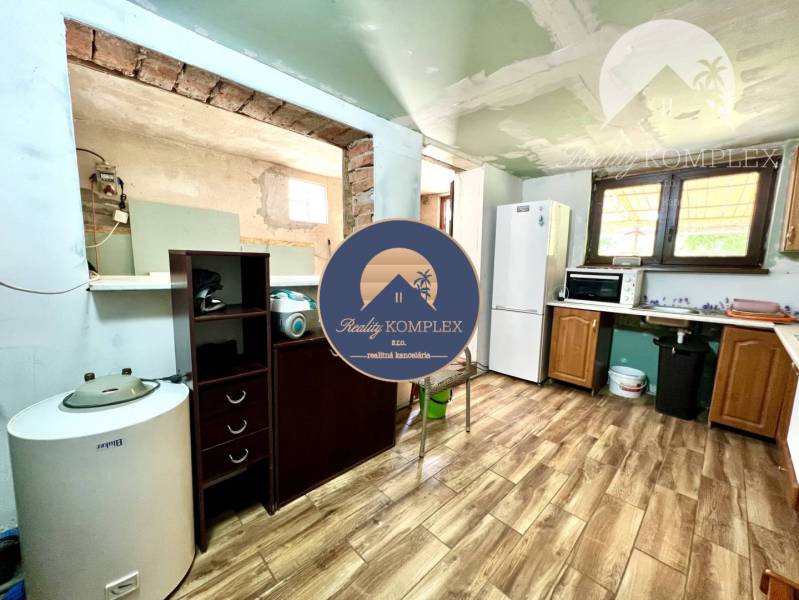 Ponúka na PREDAJ viničný domček s priestranným  - Kuchyňa v Chate so spotrebičmi, dreveným nábytkom a dlažbou na podlahe.