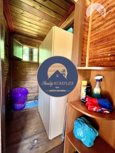 Ponúka na PREDAJ viničný domček s priestranným  - Drevený interiér s policami a prádlovým košom v chate.