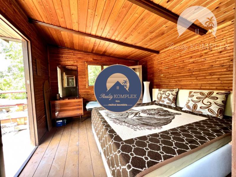 Ponúka na PREDAJ viničný domček s priestranným  - Drevený interiér chaty s pohodlnou posteľou a drevenou podlahou.