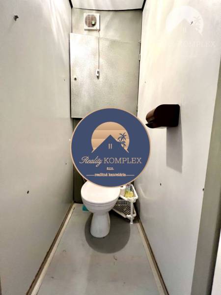 Ponúka na PREDAJ 1 izbový byt v Komárne - Toaleta v 1-izbovom byte so stenami svetlej farby a ventilátorom na strope.