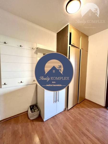 Ponúka na PREDAJ 1 izbový byt v Komárne - V 1-izbovom byte sa nachádza podlaha s dreveným dekorom, vešiaky a skrinky.