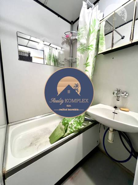 Ponúka na PREDAJ 1 izbový byt v Komárne - Kúpeľňa v 1-izbovom byte s vaňou, sprchovým závesom a umývadlom.