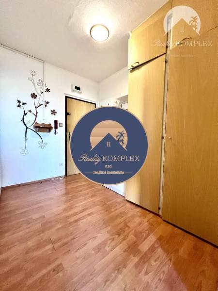 Ponúka na PREDAJ 1 izbový byt v Komárne - Interiér 1-izbového bytu s podlahou s dreveným dekorom a vstavanou skriňou.