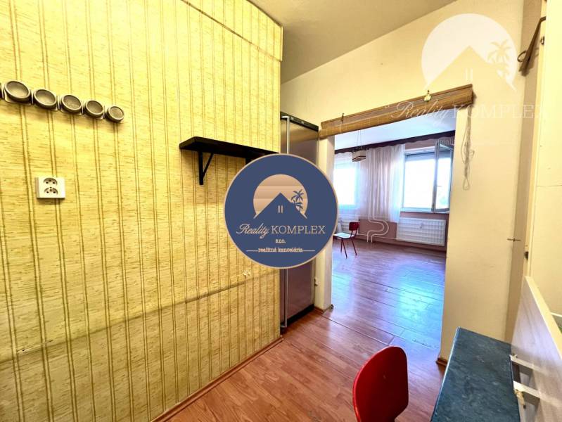 Ponúka na PREDAJ 1 izbový byt v Komárne - V 1-izbovom byte je podlaha s dreveným dekorom a stenová polica.