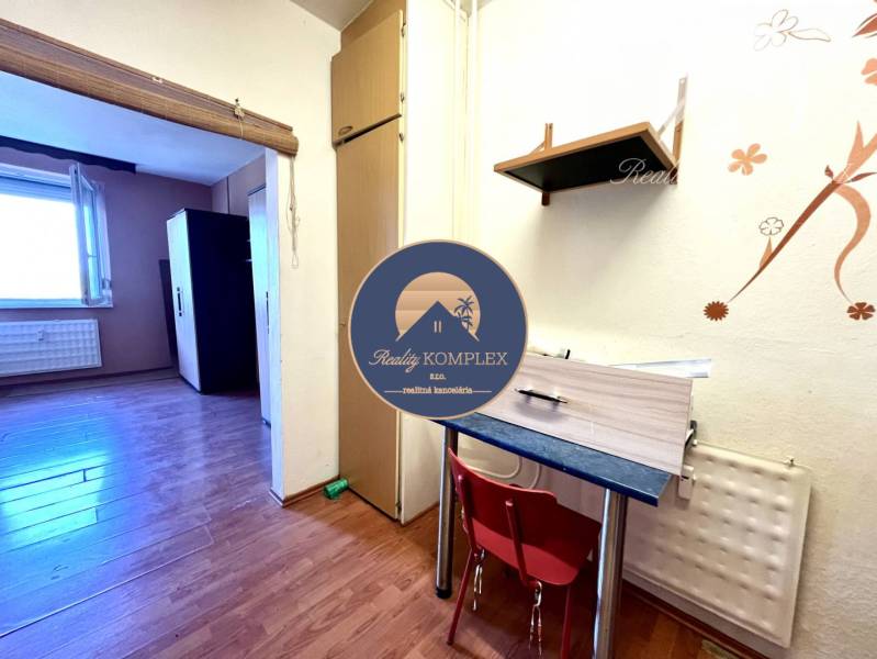 Ponúka na PREDAJ 1 izbový byt v Komárne - 1-izbový byt s podlahou s dreveným dekorom, nábytok a dekorácie na stene.