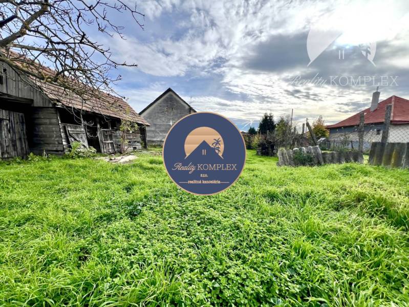 Vám ponúka na PREDAJ pozemok so starším rodinný - Pozemky - bývanie v Orechovej Potôni so starými budovami a zelenou trávou.