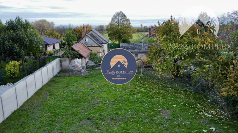 Investičný pozemok s obývateľným domom vo Vrakúni - Záhrada a starší dom v Vrakúni s oplotením a stromami v pozadí.