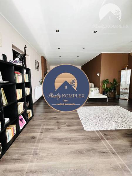 Vám ponuka na predaj útulný 3-izbový rodinný d - Obývacia izba v rodinnom dome s policami a podlahou s dreveným dekorom.