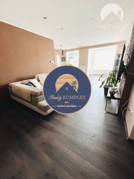 Vám ponuka na predaj útulný 3-izbový rodinný d - Obývacia izba s podlahou s dreveným dekorom a svetlými stenami v rodinnom dome.