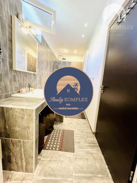 Vám ponuka na predaj útulný 3-izbový rodinný d - Kúpeľňa v rodinnom dome s dlaždicovou stenou, umývadlom a zrkadlom.