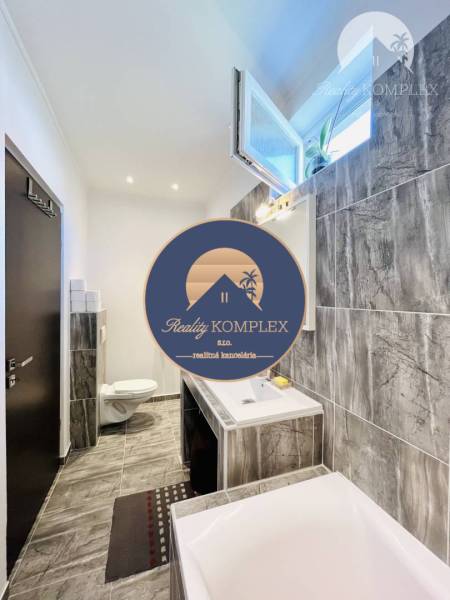 Vám ponuka na predaj útulný 3-izbový rodinný d - Kúpeľňa v rodinnom dome s keramickým obkladom a vaňou, viditeľné umývadlo a toaleta.